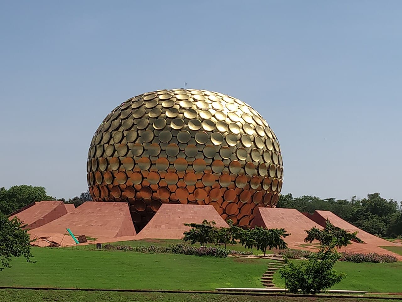 Matrimandir surrounded by red earth and green gardens